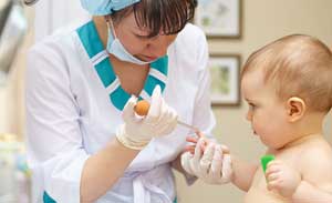 врач берет кровь из пальца у младенца