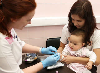 врач берет у ребенка кровь из пальца